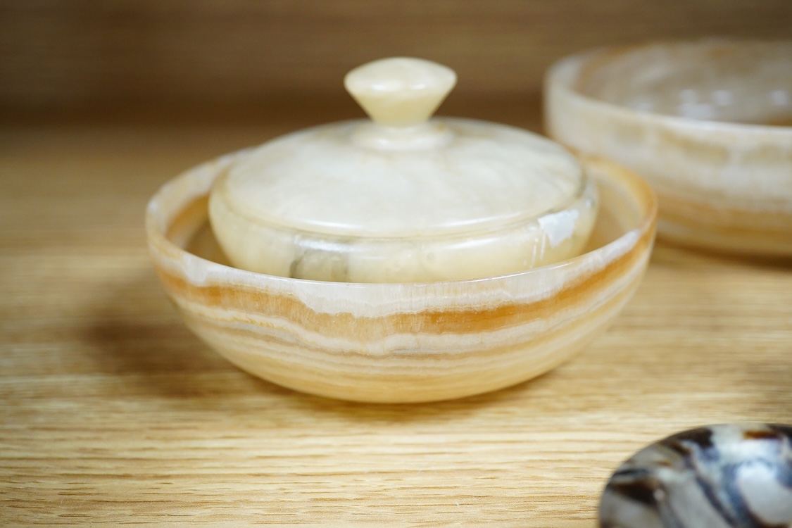 Two petrified wood ashtrays, a malachite rock, three onyx bowls, one with cover, and one other item, larger ashtray 17.5cm wide